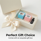 Two small containers with printed designs and a dropper bottle in an open gift box with a bow.