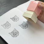 Rubber stamp with cat design being used on a piece of paper